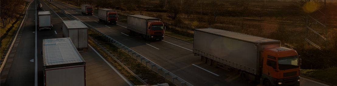 Fleet of trucks driving on the road during a sunset